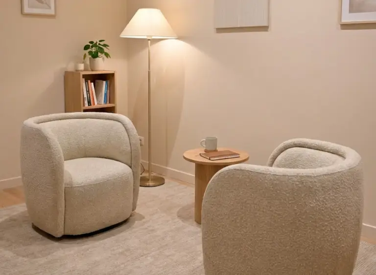 Professional coaching space with two facing sofas, warm lighting, and calming neutral decor designed for 1:1 coaching sessions and therapeutic conversations